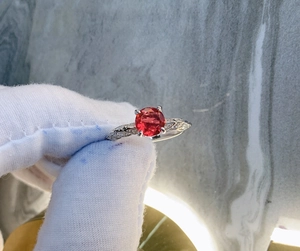 Detail of a vintage sterling silver ring with a red round ruby and pavé set diamonds
