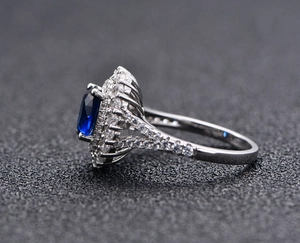 Vue latérale macro d'une bague émeraude bleue ovale avec double sertissage de zircons