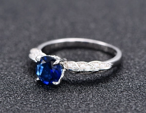 Detail of s925 silver ring with blue center stone and leaf-shaped diamond band