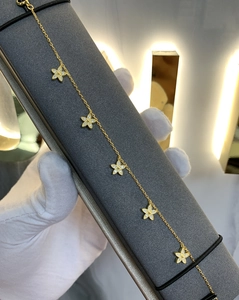 Détail macro d'un bracelet doré à trèfles à cinq feuilles sertis de zircons blancs