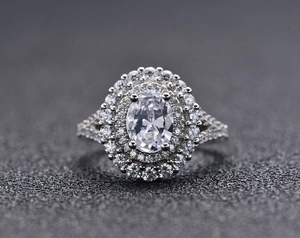 Détail d'une bague avec émeraude ovale et double halo de diamants sur monture en argent