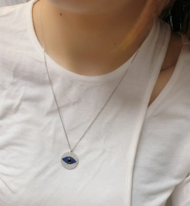 Close-up of S925 sterling silver evil eye pendant necklace worn on a model's collarbone