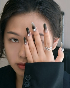 Close-up of V-shaped silver ring and black ombre press-on nails on a model