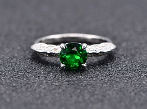 Close-up of a s925 silver ring featuring a round green zircon and pavé side stones