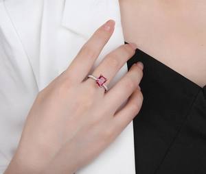 Macro view of a rectangular red emerald cut stone ring on a model with sparkling stones