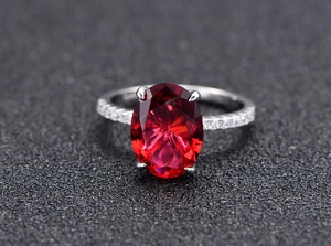 Detailed macro view of an oval cut red gemstone ring with S925 silver four-prong setting