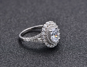 Macro d'une bague avec pierre taille émeraude ovale et monture halo sur argent