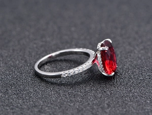 Macro detail of oval red gemstone ring with micro-pave setting and silver band