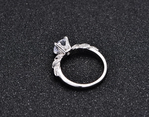 Detail view of a classic six-prong sparkling diamond ring with feather-shaped band