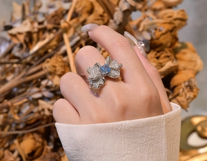 Detail of butterfly wing ring with light blue center stone and diamonds on model