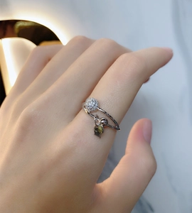 Close-up of 925 sterling silver ring with pavé zircon ball and green teardrop pendant