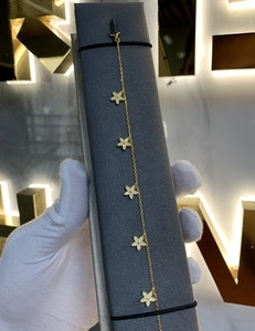 Vue détaillée d'un bracelet en or 18 carats avec cinq pendentifs trèfle scintillants