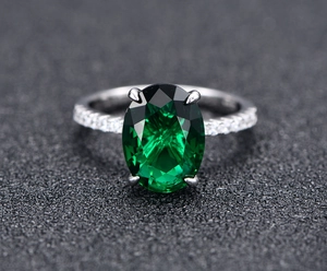 Macro view of oval green gemstone ring with white side stones on 925 silver band