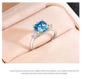 Macro view of blue princess-cut stone in a 925 silver setting on champagne silk