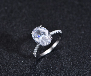 Detailed close-up of 9x12mm oval cut gemstone ring with four-prong setting and side diamonds
