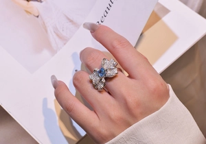 Detail of a silver butterfly ring with blue square gemstone worn on an index finger