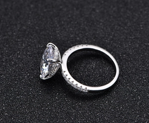 Macro side view of marquise cut gemstone ring with six-prong setting and pavé side stones