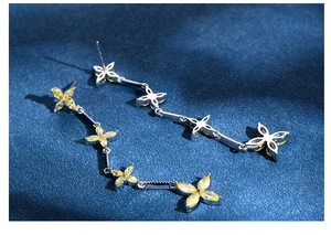 Macro detail of silver tassel earrings with yellow marquise-cut floral gemstones