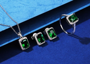 Makroaufnahme von Silberschmuck-Set mit grünen Edelsteinen auf dunkelblauem Display