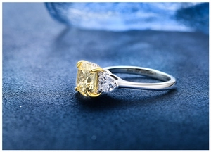 Macro detail of silver ring featuring a yellow cushion-cut gem with pear-shaped side diamonds
