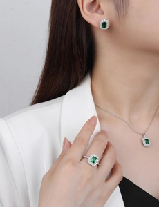Close-up of elegant S925 silver emerald jewelry set worn by model in white suit