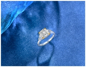Macro shot of cushion cut gemstone ring with trillion side stones on a blue background