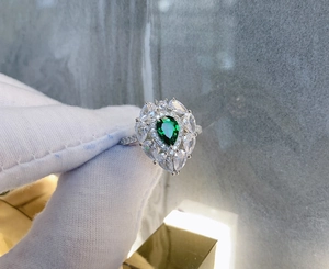 Macro detail of teardrop emerald ring with halo of cubic zirconia in silver setting