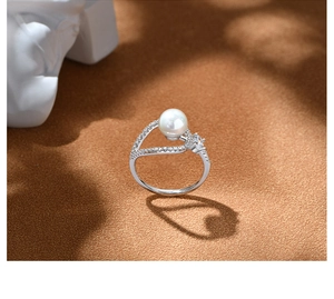Artistic detail of 925 silver pearl ring casting a heart-shaped shadow on textured surface