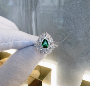 Detailed macro of S925 silver ring featuring pear-cut emerald stone and zircon halo