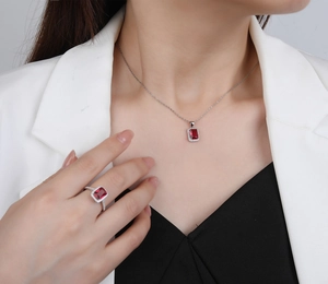 Detailaufnahme von rechteckigem rotem Edelsteinanhänger und passendem Ring am Model getragen