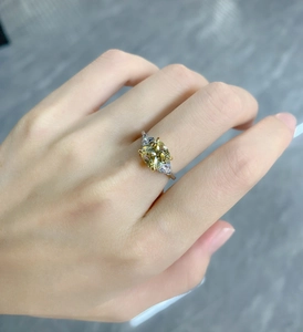 Close-up of a silver ring with a yellow cushion-cut stone and triangular side gems