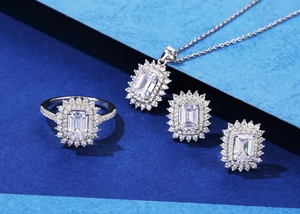 Detailed set of silver jewelry with emerald cut green gemstones and diamond halos