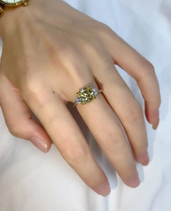 Detail of a square yellow gemstone ring with triangle side stones on a model hand
