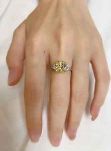 Three-stone ring featuring yellow cushion-cut center stone and white side diamonds