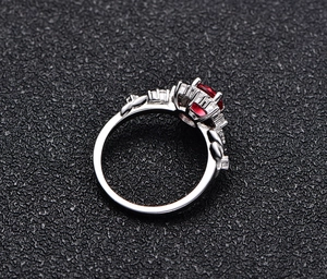 Macro detail of silver ring featuring red gemstone with floral pave diamond setting