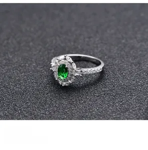 Macro shot of silver ring featuring oval green gemstone and marquise zirconia clusters