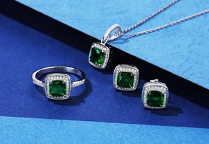 Detailed view of S925 silver jewelry set with emerald cut green stones and halo diamonds