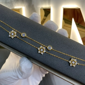 Makro-Detail des vergoldeten Schicht-Armbands mit Schneeflocken-Anhängern und Zirkonia-Steinen