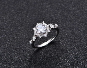 Macro view of four-prong round cut moissanite ring with halo petals and silver band