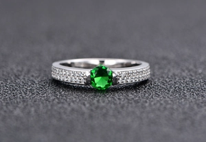 Macro shot of S925 silver ring featuring round green emerald and pave set zircons