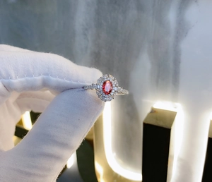 Detailed macro of a 925 sterling silver ring with oval red gemstone and halo diamonds