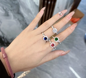 Detail of four colorful sunflower-shaped rings with red, blue, green and clear stones