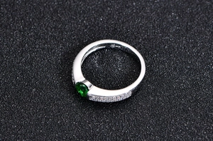 Macro shot of 925 sterling silver ring with green gemstone and micro-pave zircon detailing