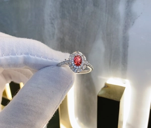 Macro detail of oval red gemstone ring with double halo pavé cubic zirconia setting