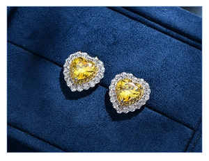 Macro shot of heart-shaped yellow diamond earrings in a blue velvet jewelry box