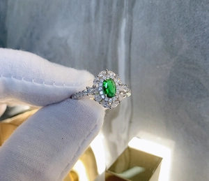 Detailed close-up of emerald style oval ring with petal-shaped zircons on silver band