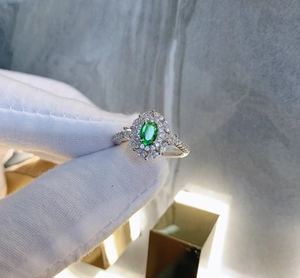 Macro shot of 925 silver ring featuring an oval green gemstone with double diamond halo