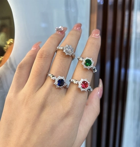 Close-up of four-prong rings with emerald, ruby, and sapphire stones on twisted bands