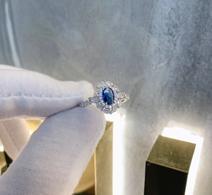 Macro shot of 925 sterling silver ring featuring oval blue gemstone and zircon halo