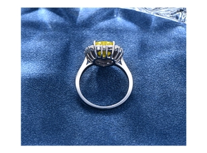 Macro shot of yellow heart-shaped gemstone ring with halo diamonds on blue surface